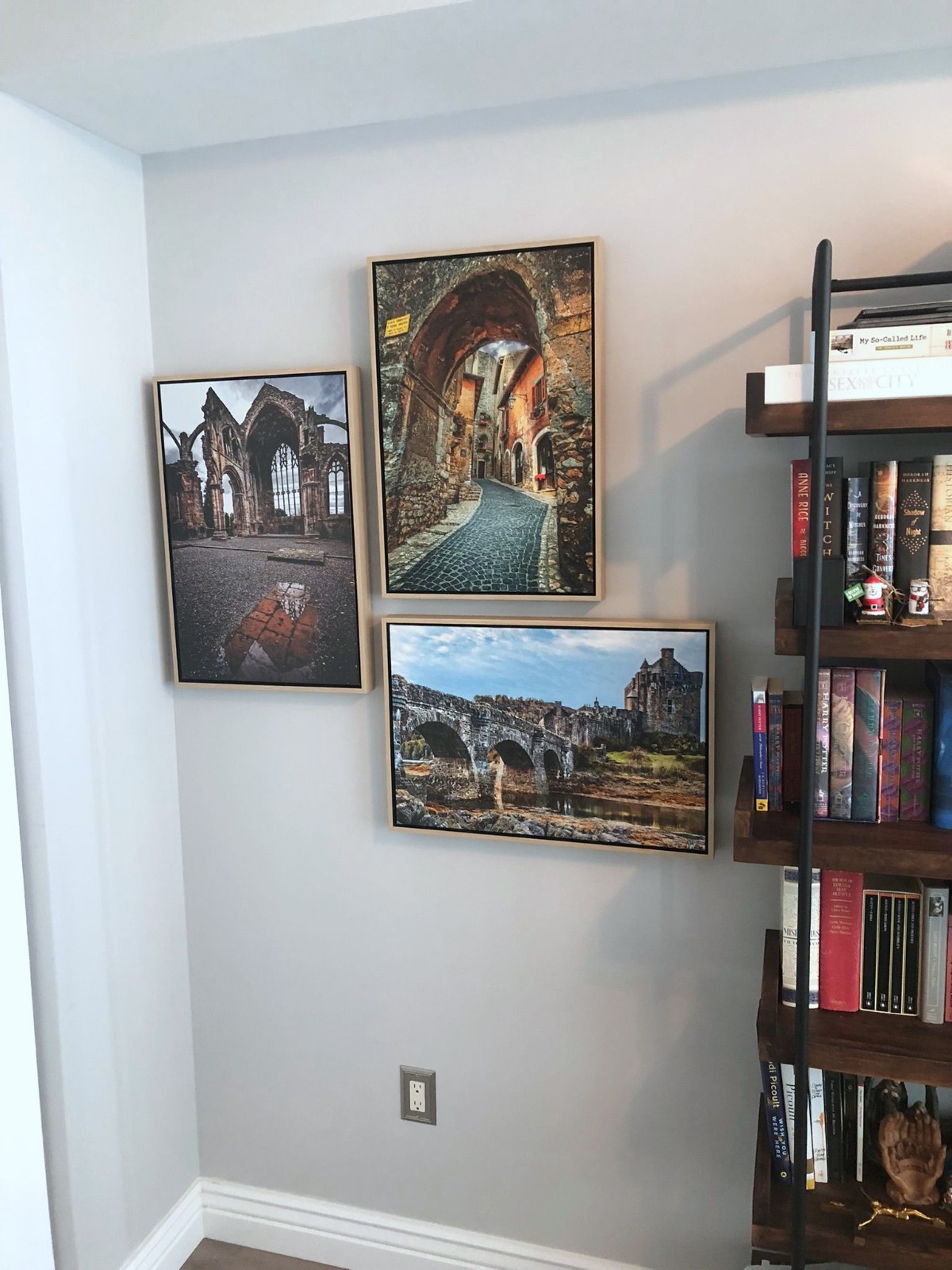 Mixed ornate and wood frames beside a bookcase.