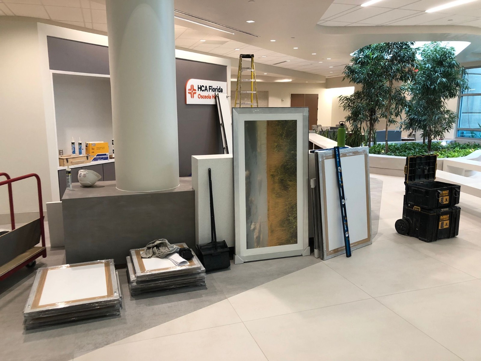 Professional install in progress with ladders and wrapped art at a hospital lobby.