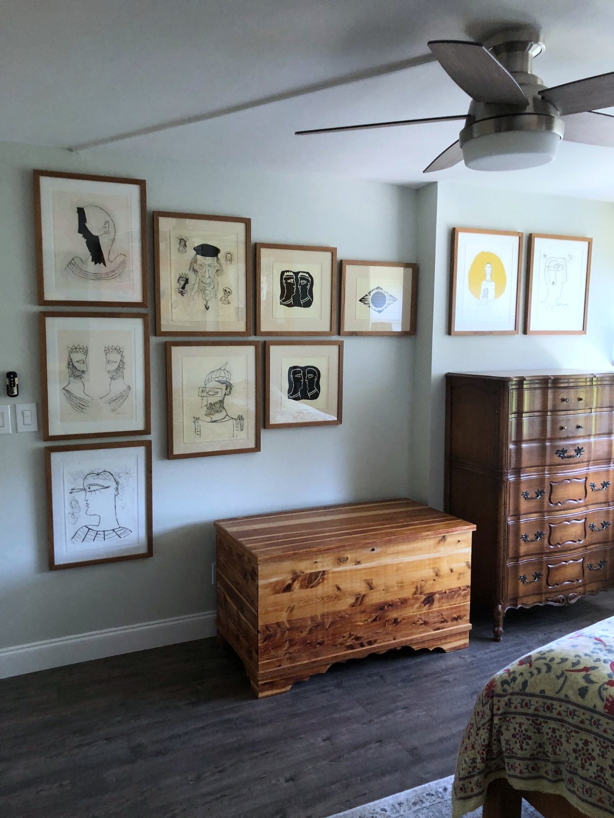 Salon of drawings in matching light wood frames.