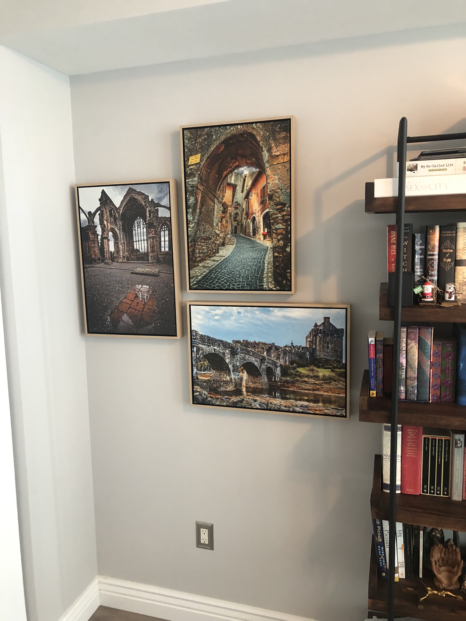 Travel photos in matching wood floaters by a bookcase.