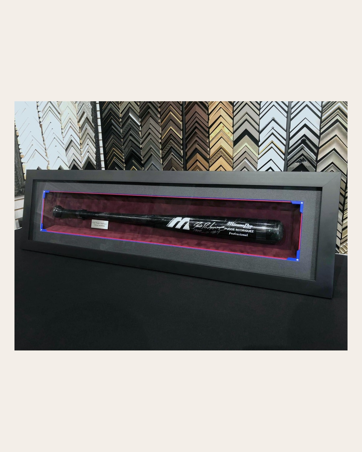 Signed Pudge Rodriguez Mizuno Pro bat in a black shadowbox with burgundy backing — full frame visible.